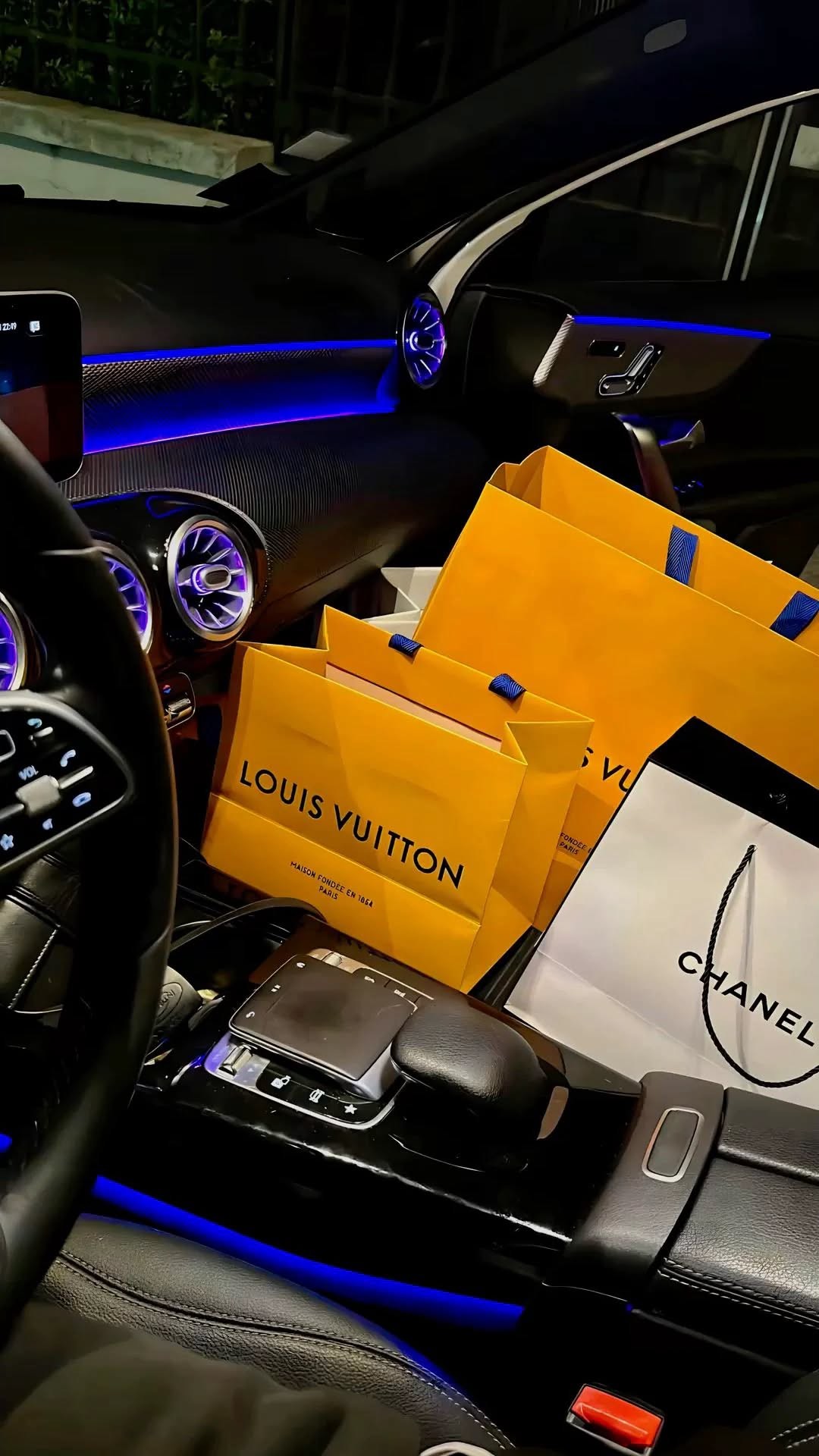 Shopping bags stacked on a car console with blue ambient lighting