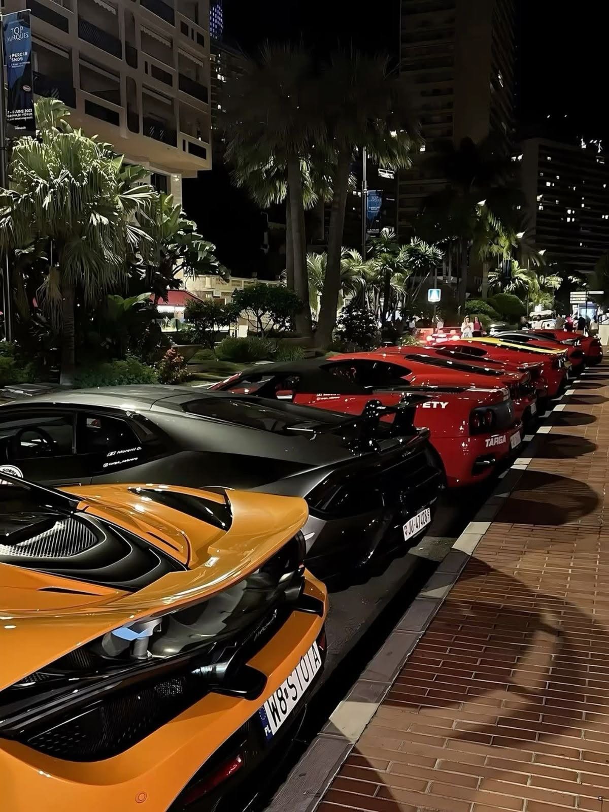 Line of parked supercars along a night boulevard